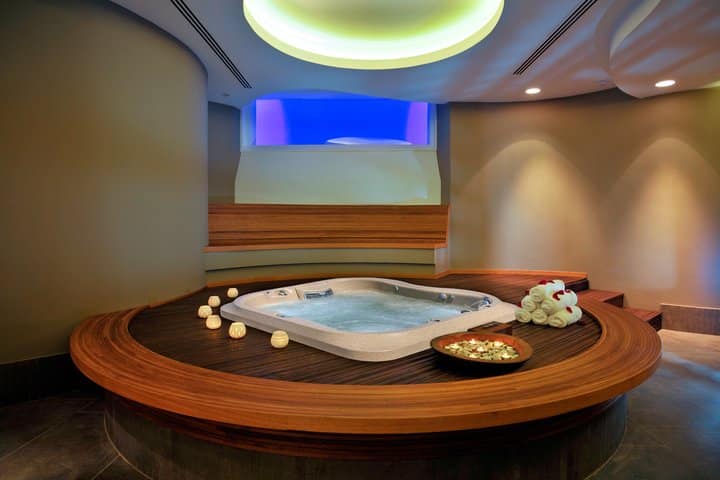 an indoor hot tub with candles and towels beside it